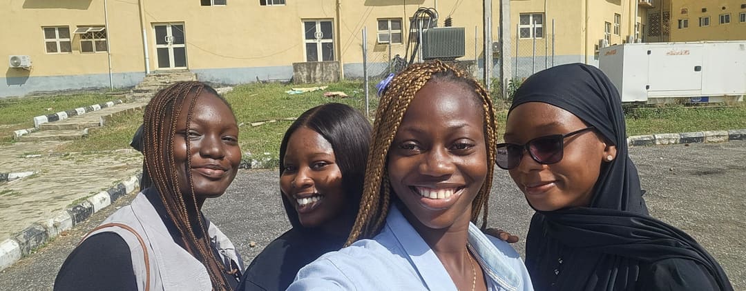 Eniola, Damilola, Bolu and Mariam, left to right, taking a selfie in front of a yellow building